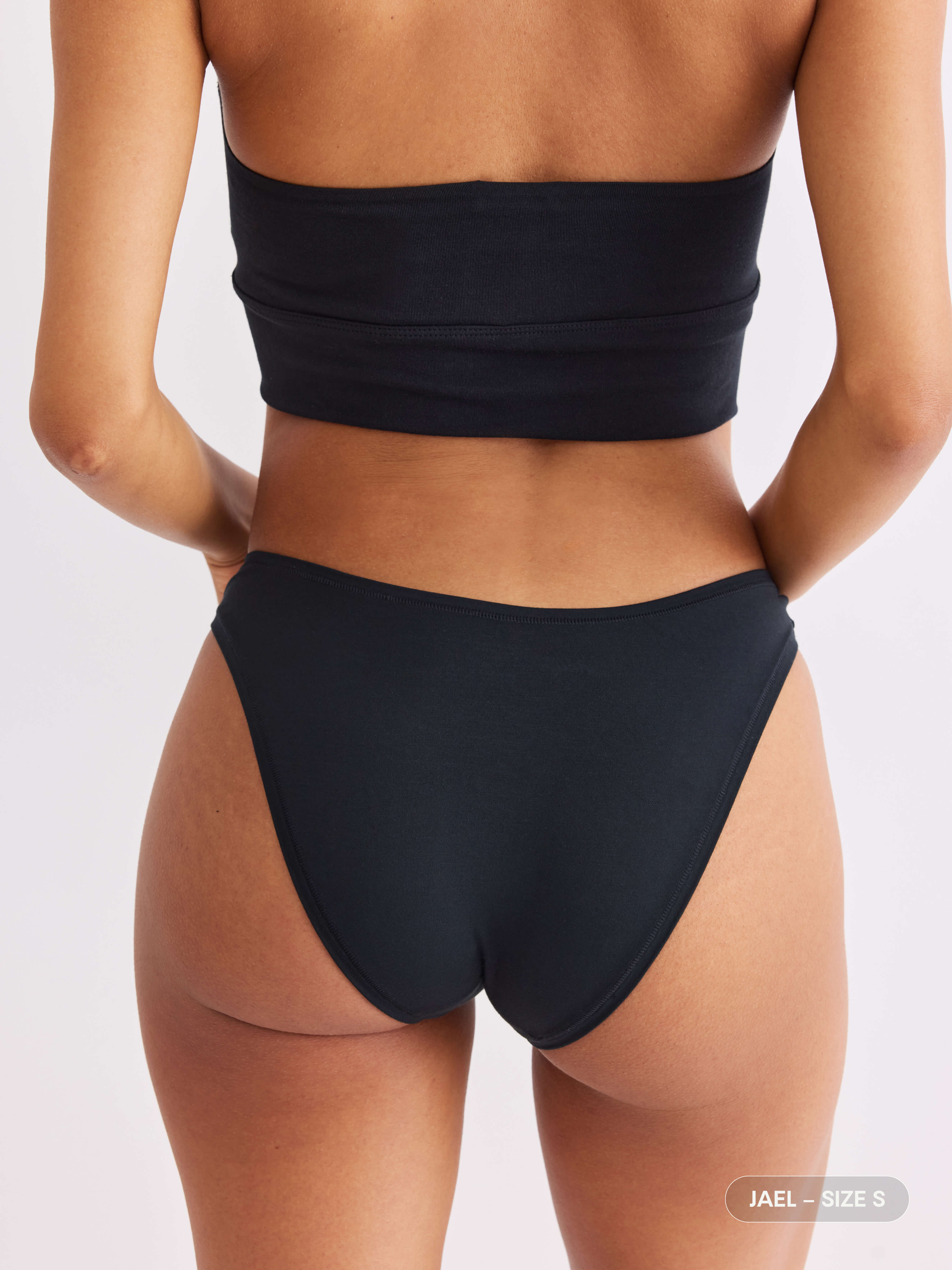 model A wearing vesper black pair of sustainable non-toxic women's underwear back view #color_vesper