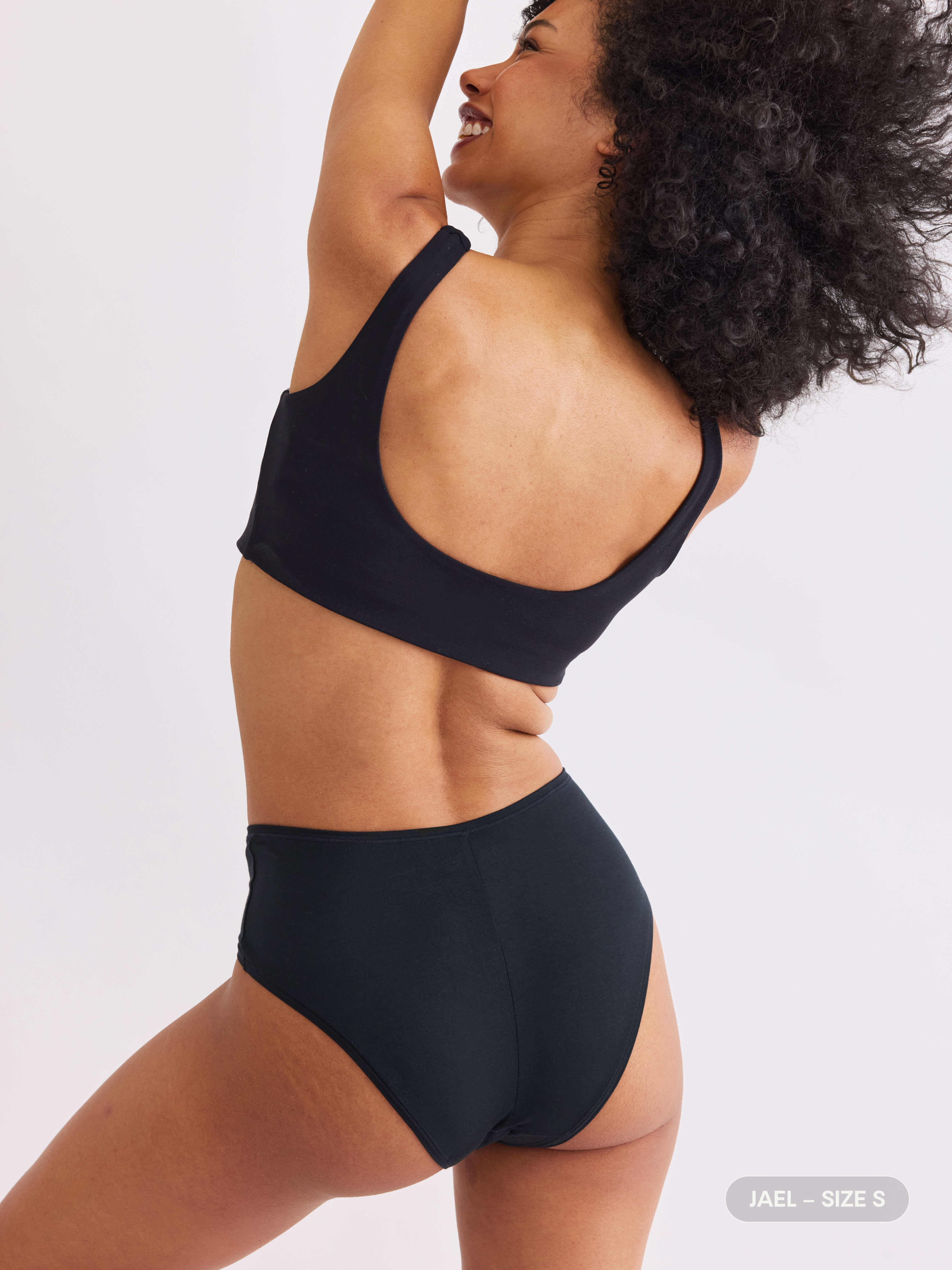 model C wearing black pair of sustainable non-toxic women's underwear back view