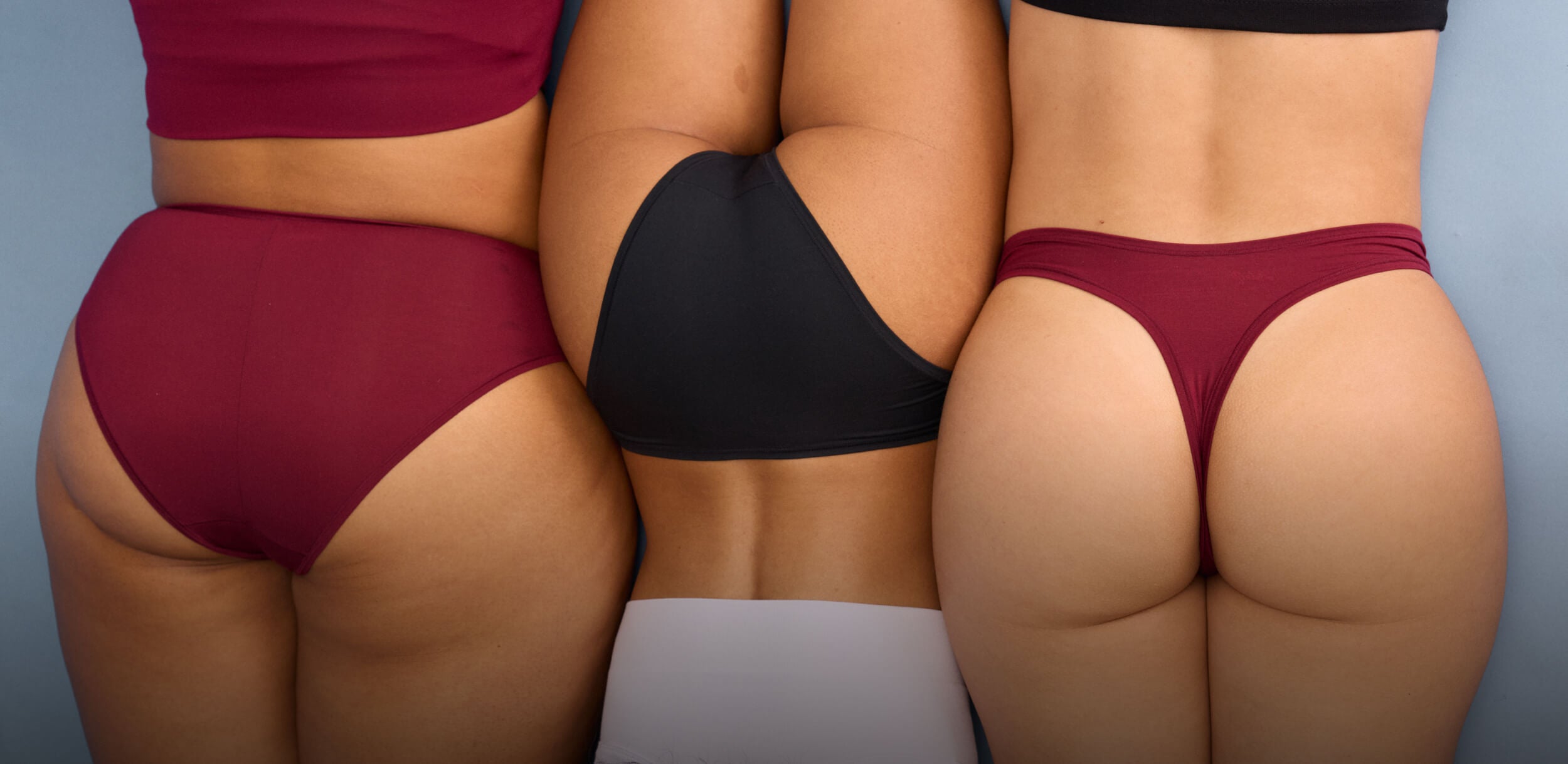 image of three women laying on a blue background wearing sustainable non-toxic underwear