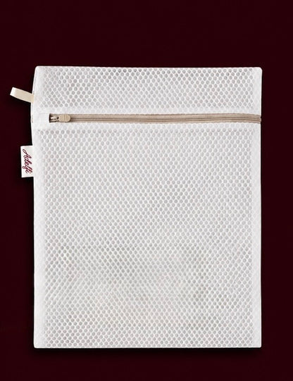 A white mesh zippered pouch with a small fabric tag on the left side, shown flat against a dark burgundy background.